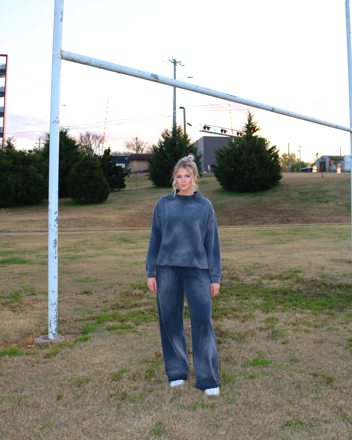 Woman standing in a grassy field with a goalpost in the background. Acid Wash Mock Neck Sweatshirt in Navy